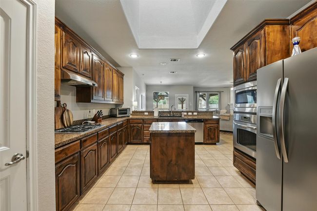 Kitchen featuring stainless steel appliances, a peninsula, recessed lighting, a kitchen island, and light tile patterned floors | Image 19