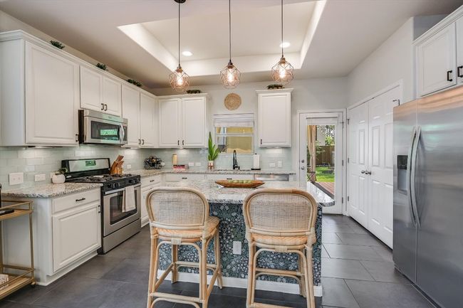 Kitchen featuring appliances with stainless steel finishes, a tray ceiling, white cabinetry, and recessed lighting | Image 14