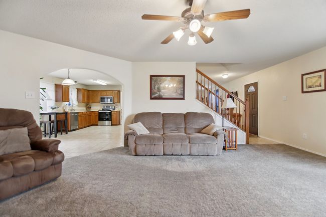 Living room featuring arched walkways, stairs, ceiling fan, and light colored carpet | Image 5
