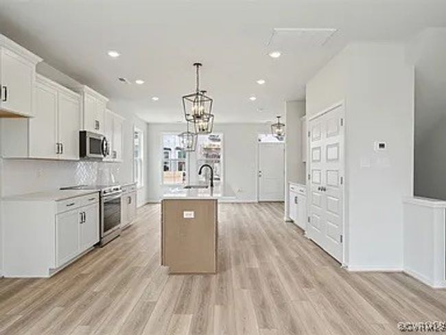 Kitchen with appliances with stainless steel finishes, an island with sink, light wood-type flooring, light countertops, and recessed lighting | Image 11