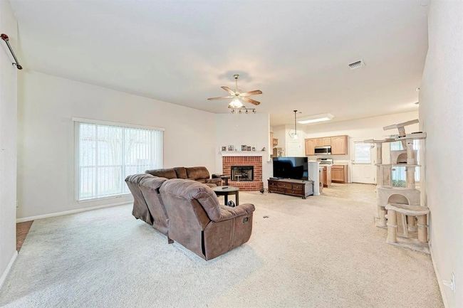 Living area with light carpet, ceiling fan, and a fireplace | Image 11