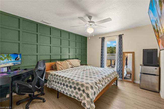 Bedroom featuring light wood-style flooring, a decorative wall, visible vents, and freestanding refrigerator | Image 10