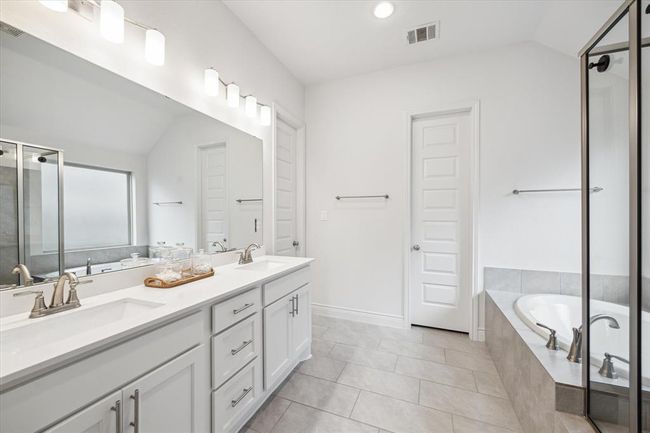 The primary en suite bathroom, featuring dual vanities and white cabinets, is a peaceful space designed to help you unwind and rejuvenate after a long day. | Image 19