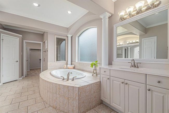 The spa-like primary en-suite bath features this wonderful oval garden tub perched beneath the window! And a fabulous vanity complete with drawers and cabinets for storage! | Image 20