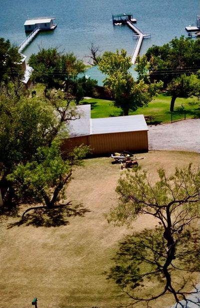 Drone photo from the street side showing yard, parking, garage, house, and dock | Image 2