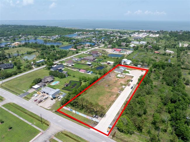 This aerial photo shows a spacious, rectangular plot of land outlined in red, with 8 residential lots and 8 more residential lots on the other side of the cul-de-sac. It's situated in a peaceful, green neighborhood with nearby homes and coastal waterfront. | Image 24