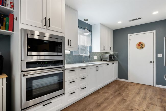 Kitchen featuring light countertops, visible vents, a sink, stainless steel microwave, and tasteful backsplash | Image 13