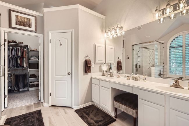 Bathroom with seamless glass shower, brass fixtures, double vanity, a spacious closet, wood finished floors, and ornamental molding | Image 13