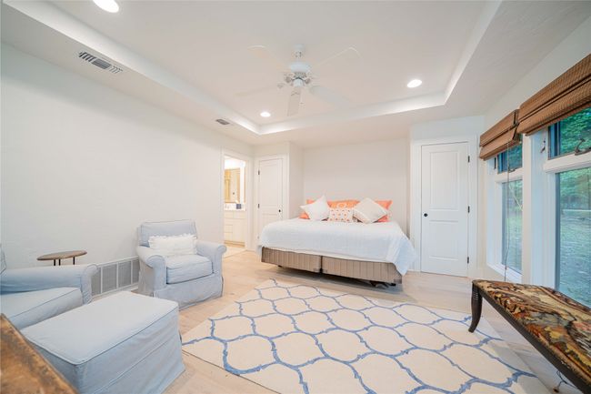 Bedroom with recessed lighting, a raised ceiling, light wood-style flooring, ceiling fan, and connected bathroom | Image 30