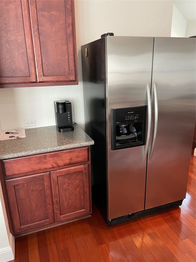 Kitchen with stainless steel fridge, dark wood-style flooring, and light stone countertops | Image 13