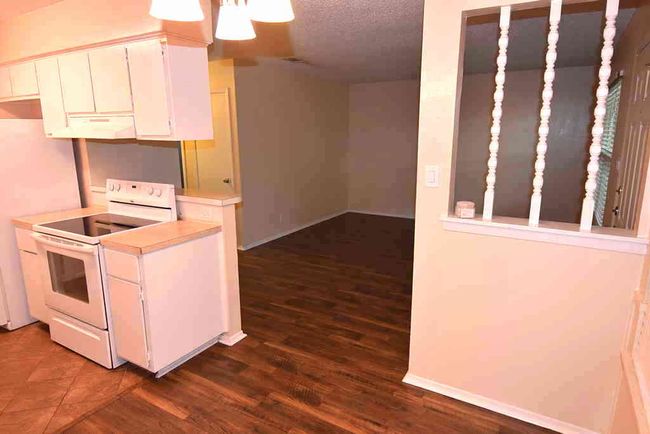 Kitchen featuring electric stove, light countertops, dark wood finished floors, white cabinetry, and fridge | Image 4