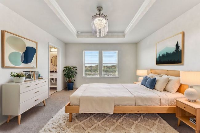 Carpeted bedroom featuring connected bathroom, crown molding, an inviting chandelier, and a raised ceiling | Image 17