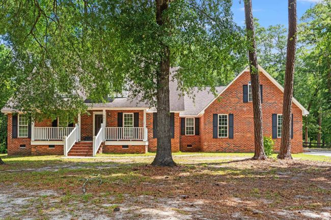 View of front of home with crawl space, a porch, a shingled roof, and brick siding | Image 32