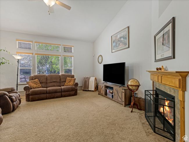 Living room featuring carpet, a tiled fireplace, lofted ceiling, and ceiling fan | Image 9