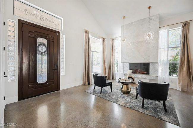 Foyer with high vaulted ceiling, baseboards, speckled floor, and a fireplace | Image 8