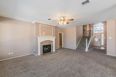 Unfurnished living room featuring dark carpet, crown molding, a tiled fireplace, and ceiling fan | Image 3