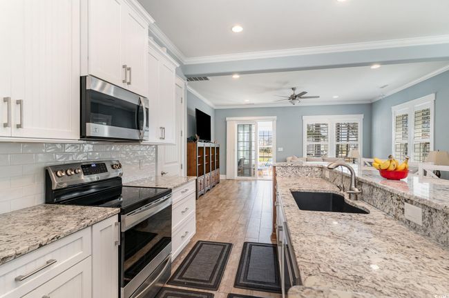 Kitchen with white cabinets, recessed lighting, stainless steel appliances, a sink, and decorative backsplash | Image 12