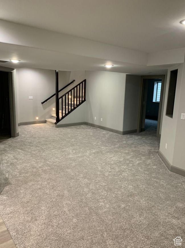 Basement with carpet floors, visible vents, stairway, and baseboards | Image 16