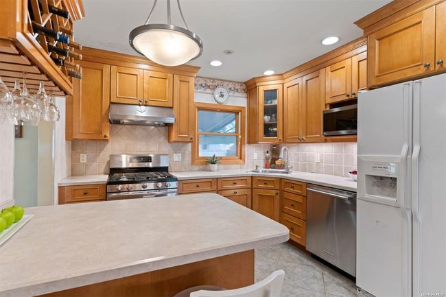 Kitchen has maple cabinets with tile backsplash & tile floor | Image 6