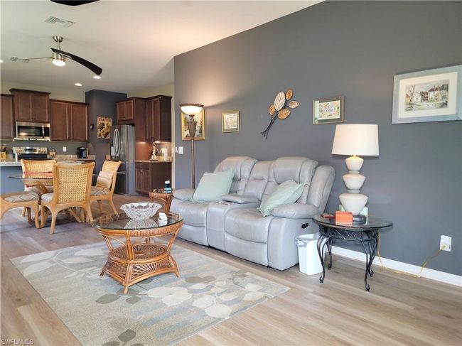 Living area with light wood-style flooring, visible vents, baseboards, and ceiling fan | Image 19