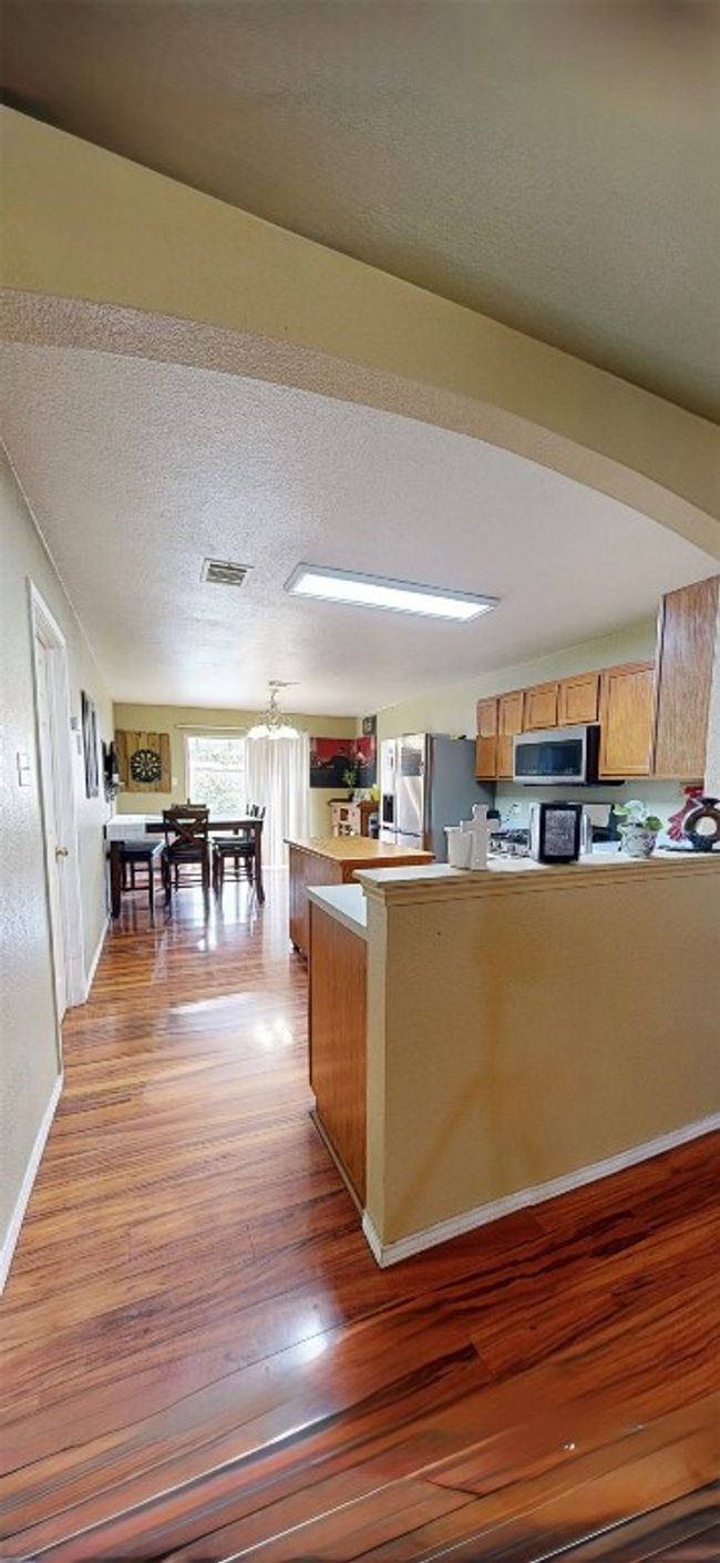 Kitchen featuring stainless steel appliances, a peninsula, light wood finished floors, a textured ceiling, and light countertops | Image 14