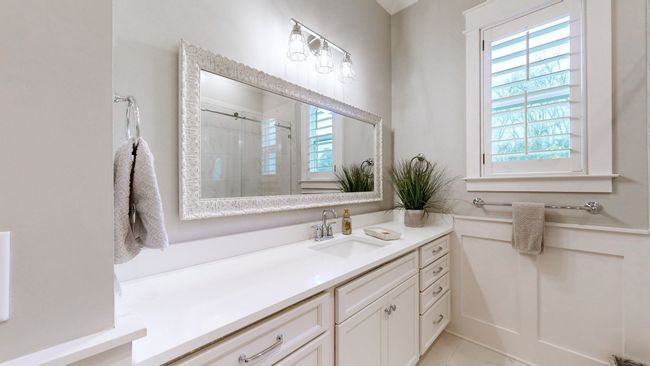 This main-level full bath features elegant wainscoting, a large framed mirror, quartz countertops, and stylish finishes—perfect for guests or everyday use with a touch of sophistication. | Image 34