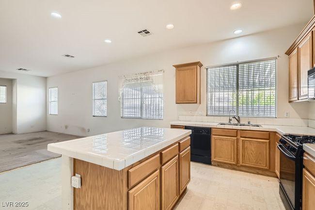 Kitchen featuring tile counters, recessed lighting, black appliances, visible vents, and a sink | Image 11