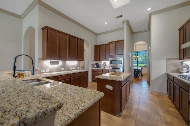 This kitchen is a chefs delight with tons of cabinets, granite countertops, center island and two pantries. One can be used for all your large baking items. Stainless steel appliances | Image 11