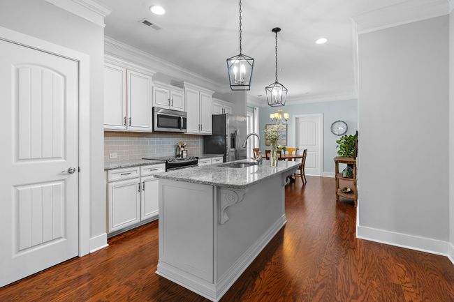 The kitchen features a custom-built island with soft-close drawers, decorative woodwork, and a granite countertop. | Image 7