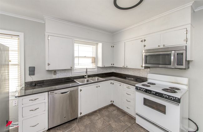 Kitchen featuring a sink, dark countertops, appliances with stainless steel finishes, and decorative backsplash | Image 14