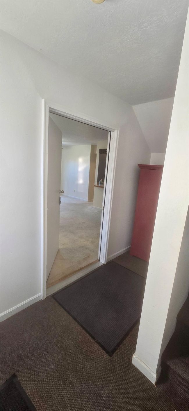 Hallway with vaulted ceiling, carpet flooring, and baseboards | Image 6