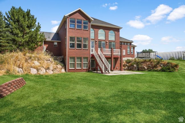 Rear view of house featuring a wooden deck, stairway, a yard, and brick siding | Image 28
