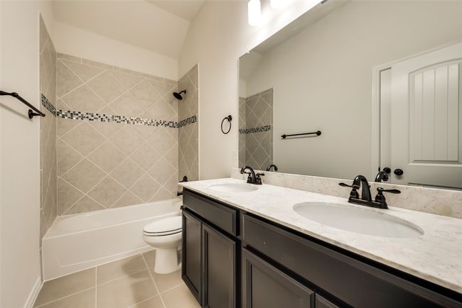 Full bathroom with double vanity, shower / bath combination, and tile patterned flooring | Image 4