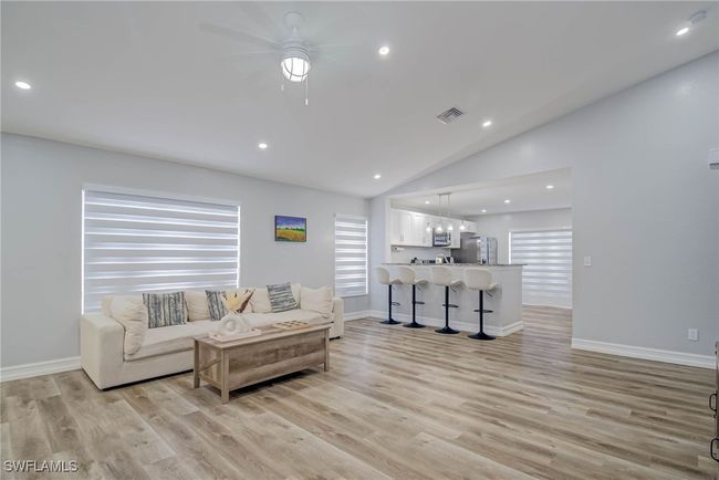 Living room with lofted ceiling, ceiling fan, light wood-style flooring, recessed lighting, and baseboards | Image 5