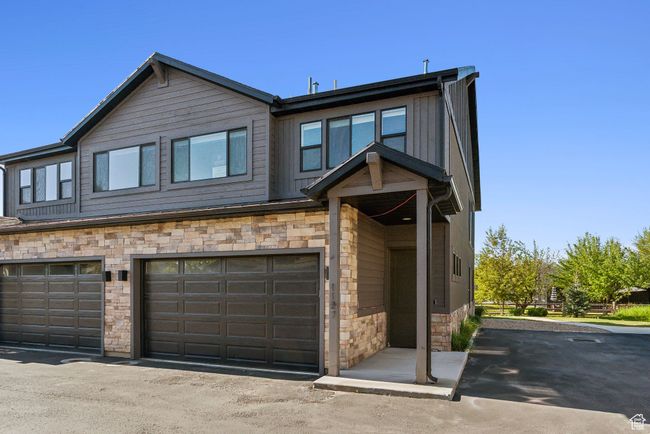 View of front of house with stone siding, an attached garage, and board and batten siding | Image 45