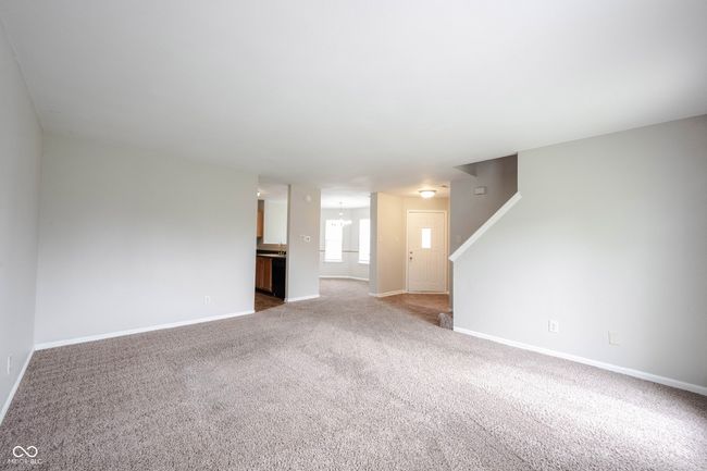 unfurnished living room featuring stairway, baseboards, and carpet flooring | Image 9