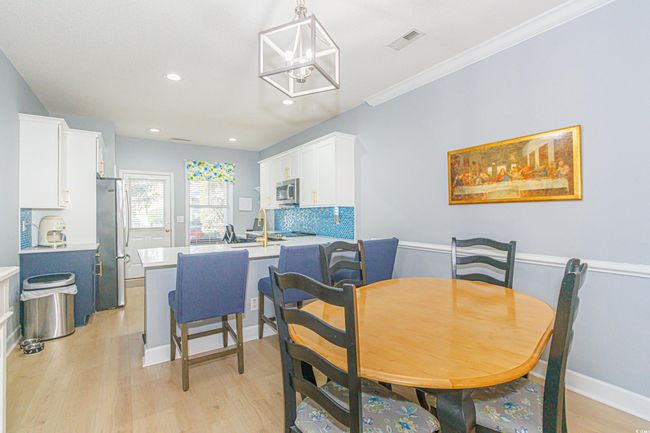 Dining space with crown molding, a notable chandelier, and light hardwood / wood-style floors | Image 9