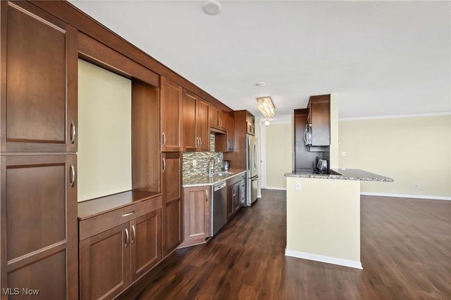 Kitchen featuring a sink, stone counters, decorative backsplash, stainless steel appliances, and dark wood-style flooring | Image 8