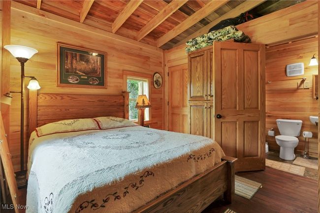 Bedroom featuring wooden walls, wood ceiling, dark wood-type flooring, and connected bathroom | Image 23