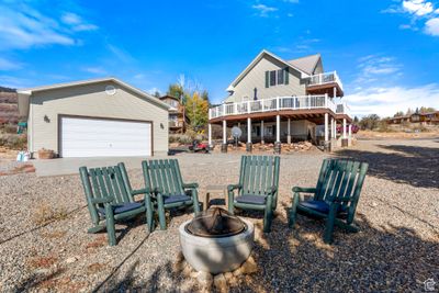 Back of property featuring a deck, a fire pit, and a garage | Image 1