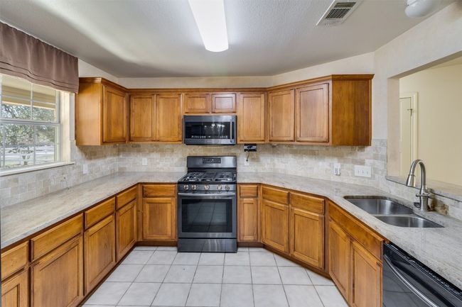 Kitchen featuring a sink, brown cabinets, backsplash, and stainless steel appliances | Image 12