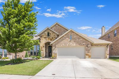 Welcome home to this beautiful home with open land space behind. View of front of property featuring a 3-car garage and a bonus access door from garage to backyard. | Image 1