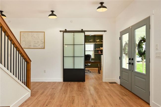Entrance foyer with double glass doors, light wood LVP finished floors, sliding modern barn door that opens to the office. | Image 10