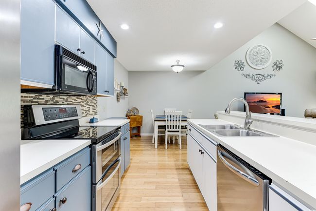 Kitchen featuring light countertops, backsplash, light wood-style floors, stainless steel appliances, and a sink | Image 4