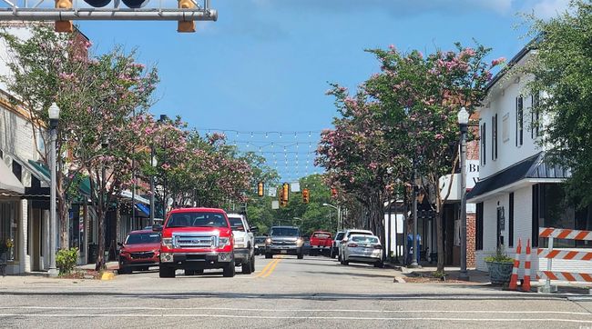 View of asphalt street featuring traffic lights, street lighting, curbs, and sidewalks | Image 25