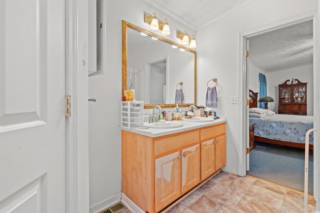 Full bathroom featuring a textured ceiling, double vanity, connected bathroom, and crown molding | Image 15