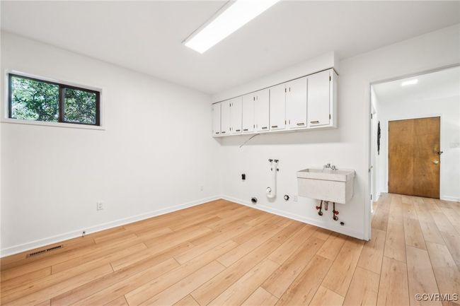 Laundry area with visible vents, gas dryer hookup, light wood-style flooring, cabinet space, and washer hookup | Image 13