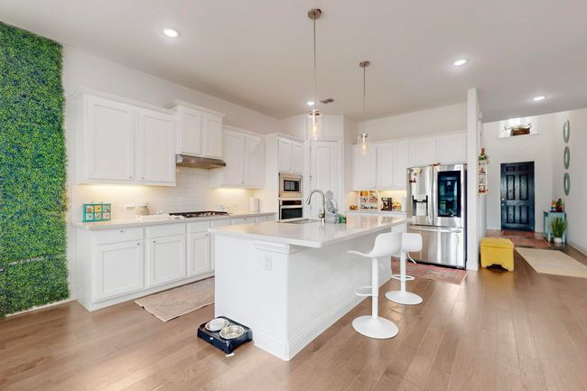 Kitchen with white cabinets, light countertops, appliances with stainless steel finishes, a kitchen island with sink, and light wood-style floors | Image 9
