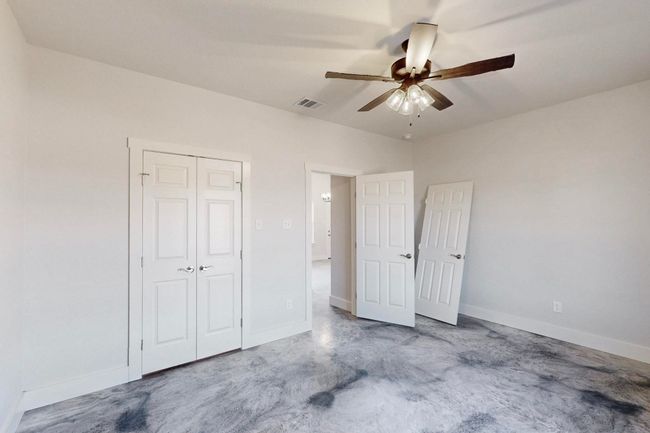 Unfurnished bedroom featuring concrete floors, a closet, baseboards, a ceiling fan, and visible vents | Image 34