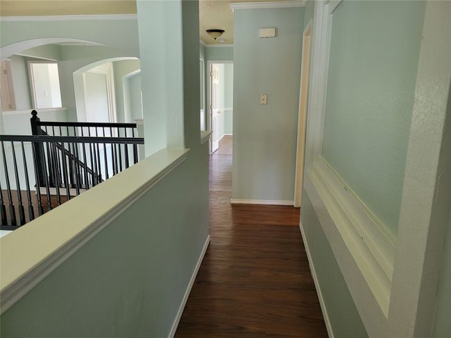 Corridor with crown molding, an upstairs landing, dark wood finished floors, and arched walkways | Image 24